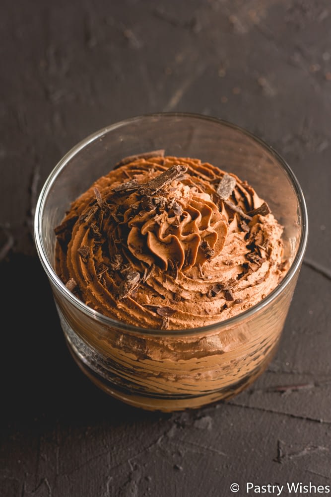 dark chocolate mousse in a glass with chocolate shavings on a dark surface
