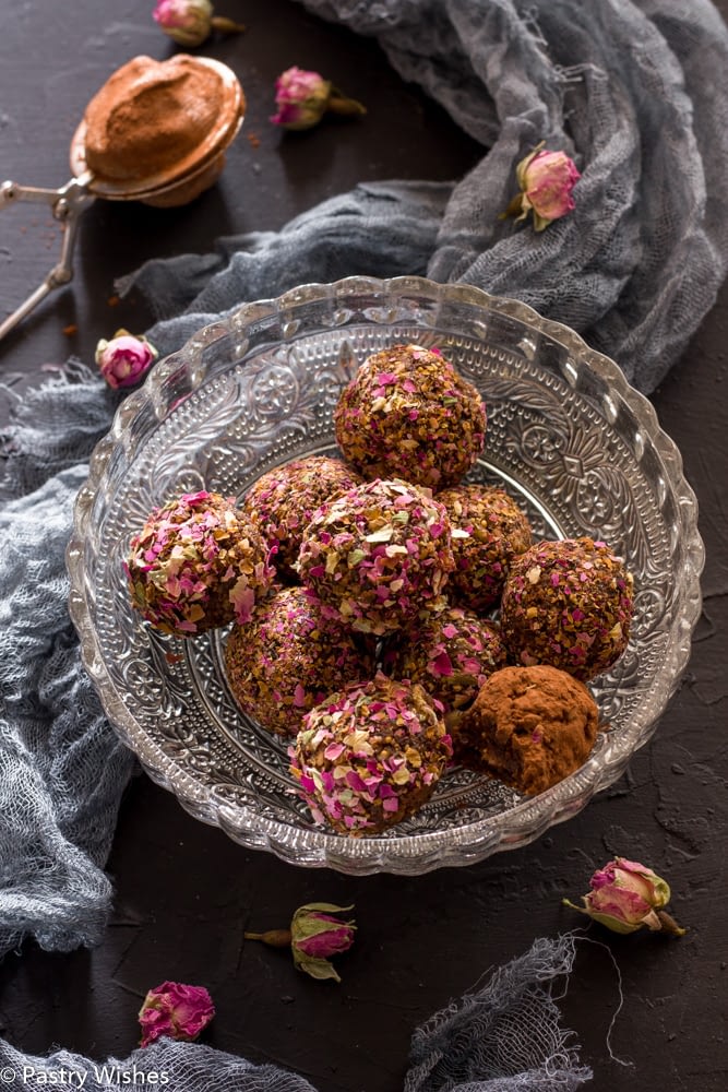 rose bliss balls in a bowl on a dark surface with gray cloth and dried rose buds