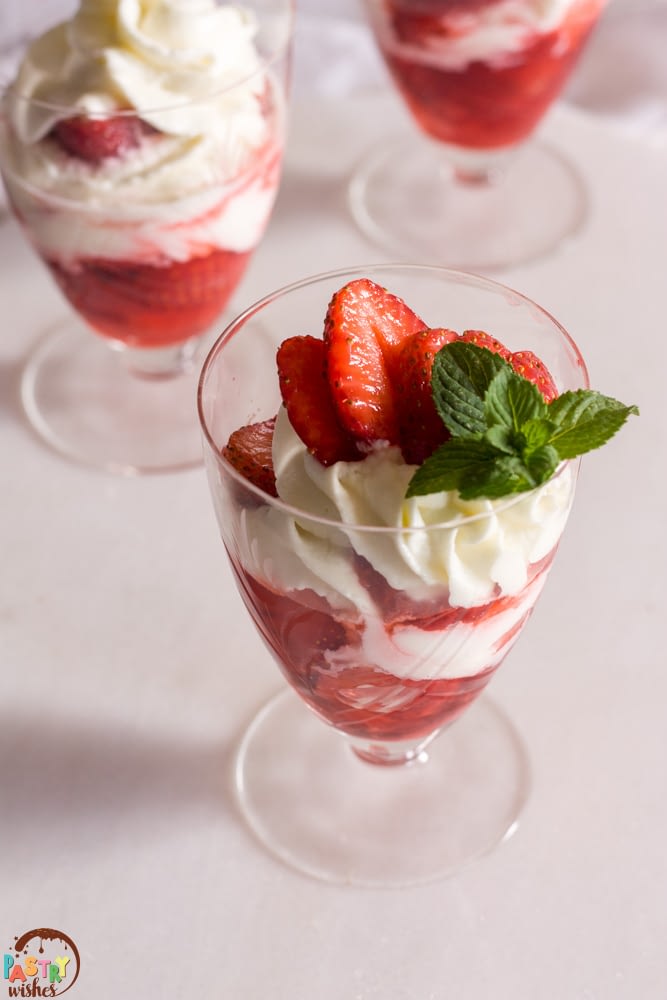no bake strawberry dessert cups with strawberries and cream on a white surface